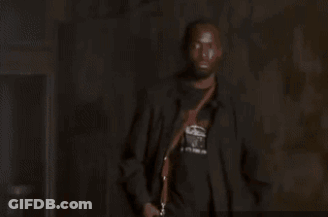 Man In Suit And Bow Tie Holding Gun In Dark Room GIF