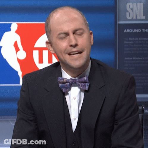 Man In Suit And Bow Tie Sitting In Front Of SNL Sign GIF