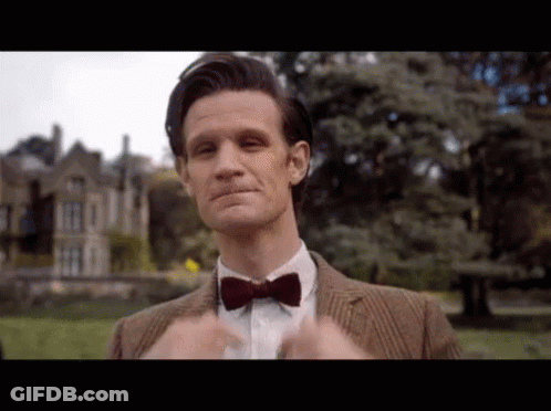 Man In Suit And Bow Tie Standing In Front Of Building GIF