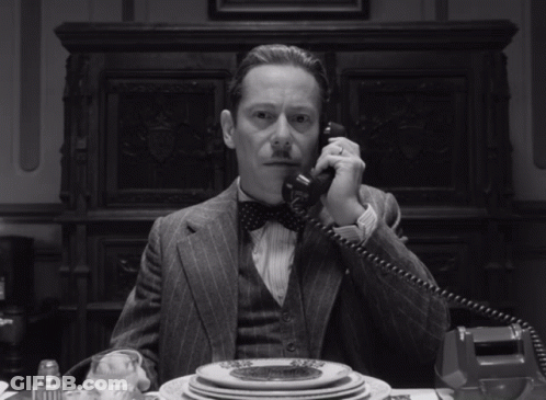 Man In Suit And Bow Tie Talking On Phone GIF