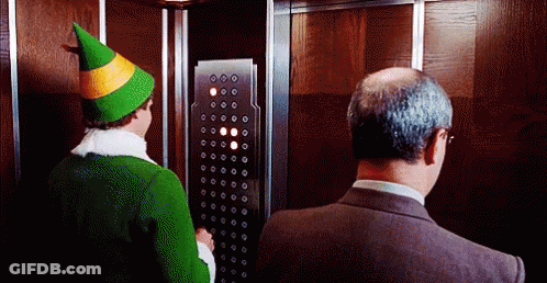 Man In Suit And Green Hat Elf In Elevator GIF