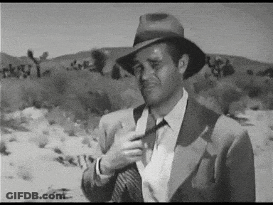 Man In Suit And Hat Adjusting Tie In Desert GIF