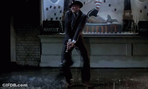 Man In Suit And Hat Dancing By Ahout Sign GIF