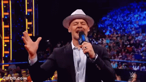 Man In Suit And Hat Holding Microphone Amid Crowd GIF