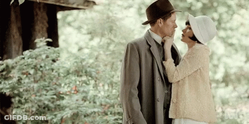 Man In Suit And Hat Kissing Woman In White Hat GIF