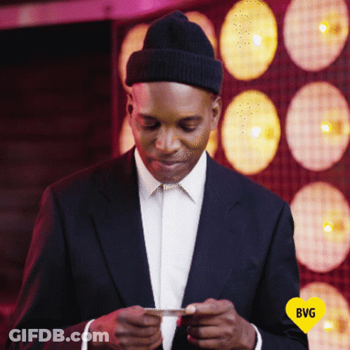 Man In Suit And Hat Looking At Phone With Yellow Heart Saying BG GIF