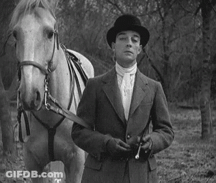 Man In Suit And Hat Standing Next To Horse GIF