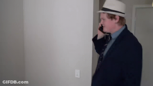 Man In Suit And Hat Talking On Cell Phone In Hallway GIF