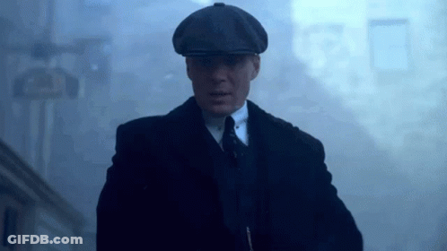 Man In Suit And Hat Walking Through Foggy Street GIF