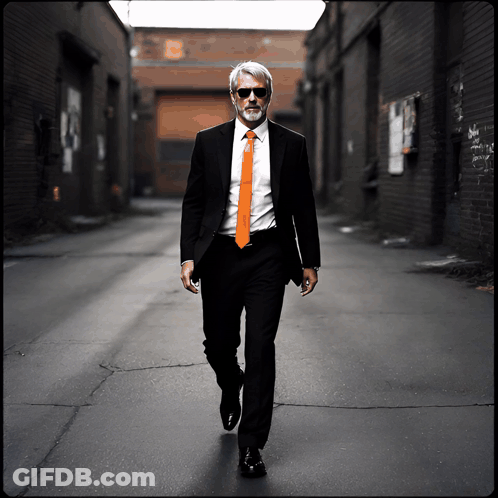 Man In Suit And Orange Tie Walking Down Alley GIF