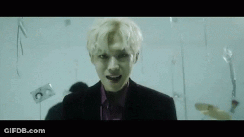 Man In Suit And Purple Shirt With Balloons In Dark Room GIF