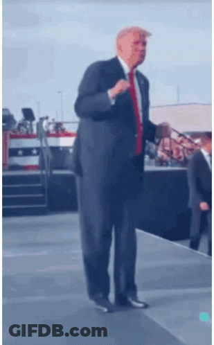 Man In Suit And Red Tie On Stage GIF