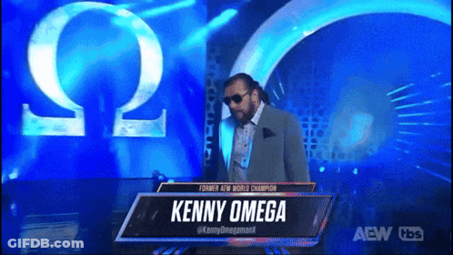 Man In Suit And Sunglasses At Kenny Omega Sign GIF