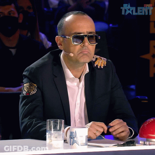 Man In Suit And Sunglasses At Table With Estrella Talent Cup GIF
