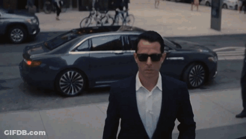 Man In Suit And Sunglasses Walking Past Car GIF