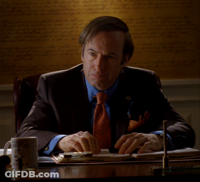 Man In Suit And Tie At Desk With Poof GIF