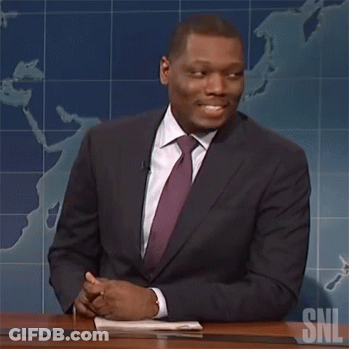 Man In Suit And Tie At Desk With SNL Logo GIF