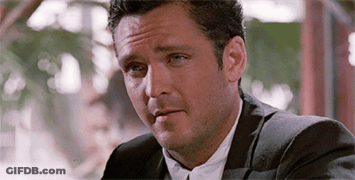 Man In Suit And Tie At Table Looking At Something GIF