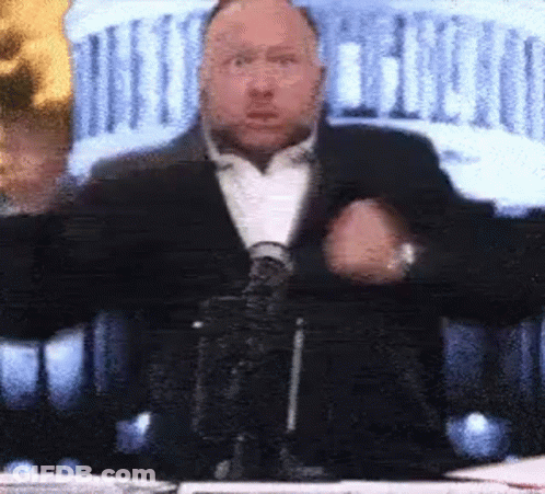 Man In Suit And Tie At Table With Microphone GIF