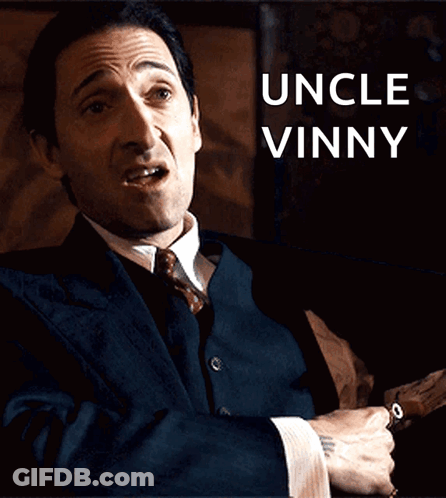 Man In Suit And Tie At Uncle Vinny Sign GIF