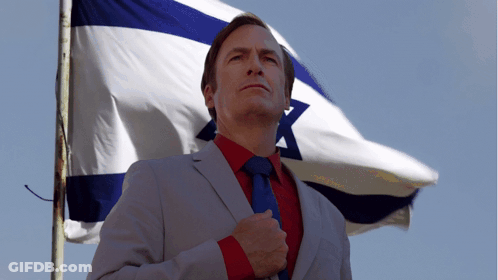 Man In Suit And Tie Before Blue And White Flag GIF