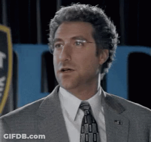 Man In Suit And Tie Before Blue Sign GIF
