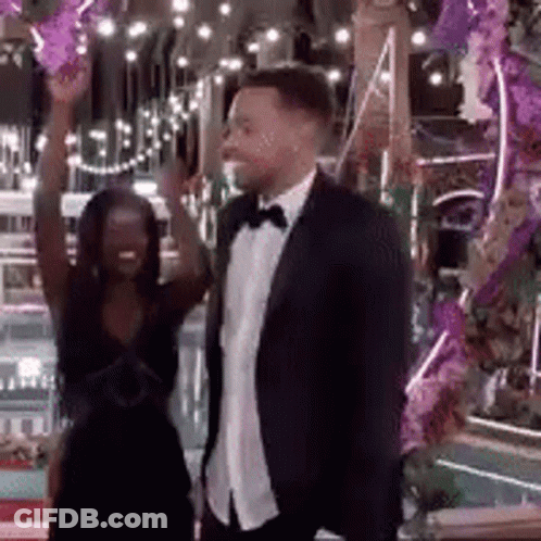 Man In Suit And Tie Beside Woman In Dress GIF