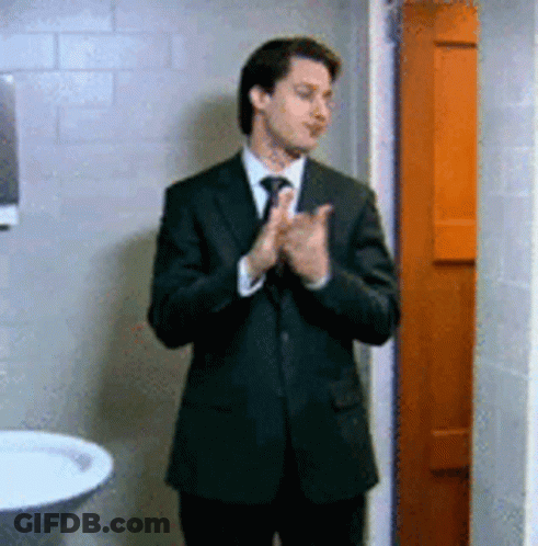 Man In Suit And Tie Clapping In Bathroom GIF