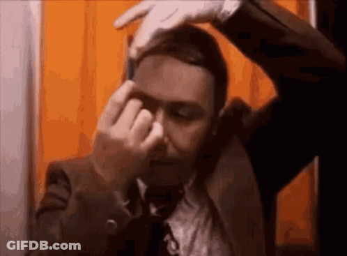 Man In Suit And Tie Covering Nose With Hands GIF