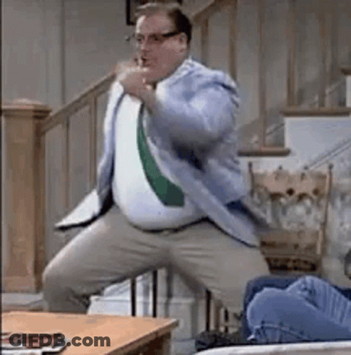 Man In Suit And Tie Dancing Next To Couch GIF