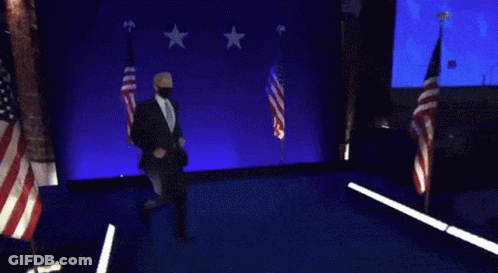 Man In Suit And Tie Dancing On Stage With American Flags GIF
