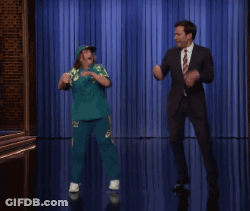 Man In Suit And Tie Dancing With Girl In Green GIF