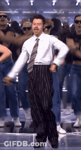Man In Suit And Tie Dancing With Group GIF