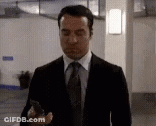 Man In Suit And Tie Holding Cellphone Hallway GIF