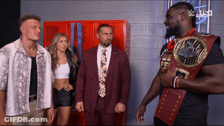 Man In Suit And Tie Holding Championship Belt Beside Two Men GIF