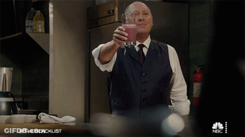 Man In Suit And Tie Holding Glass With NBC Logo GIF