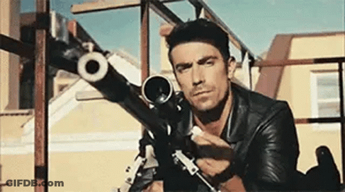 Man In Suit And Tie Holding Gun Saying The Hit Man Is Home GIF