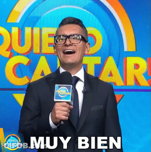 Man In Suit And Tie Holding Microphone Beside Muy Bien Sign GIF