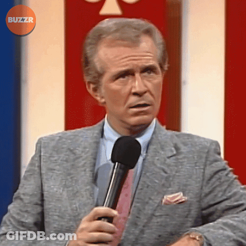 Man In Suit And Tie Holding Microphone In Front Of Buzzr Button GIF