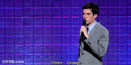 Man In Suit And Tie Holding Microphone Saying Hmm Gross GIF
