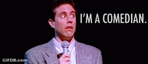 Man In Suit And Tie Holding Microphone Saying I'm A Comedian GIF