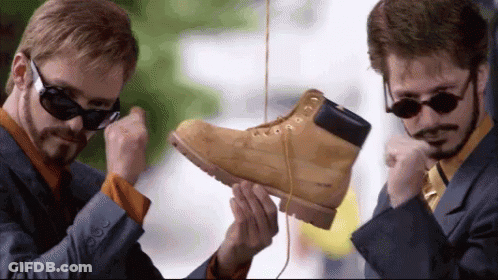 Man In Suit And Tie Holding Pair Of Boots GIF