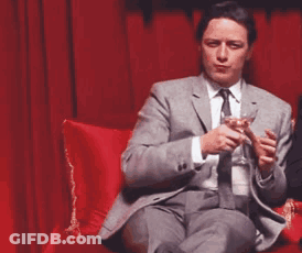 Man In Suit And Tie Holding Wine Glass On Red Couch GIF