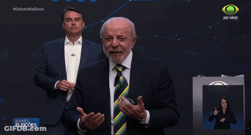Man In Suit And Tie In Front Of Band Eleioes Sign GIF