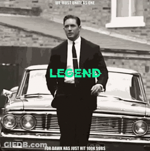 Man In Suit And Tie In Front Of Car With Legend GIF