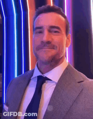 Man In Suit And Tie In Front Of Colorful Background GIF
