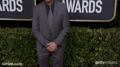 Man In Suit And Tie In Front Of Globe Awards Sign GIF