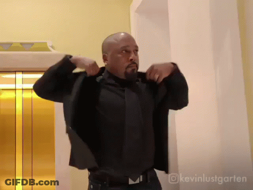 Man In Suit And Tie In Front Of Gold Elevator GIF