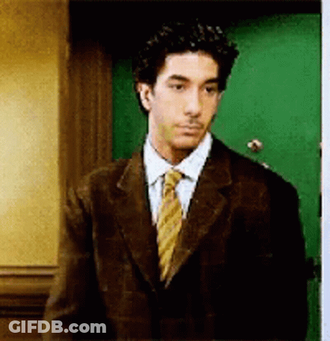 Man In Suit And Tie In Front Of Green Door GIF