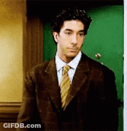 Man In Suit And Tie In Front Of Green Door GIF